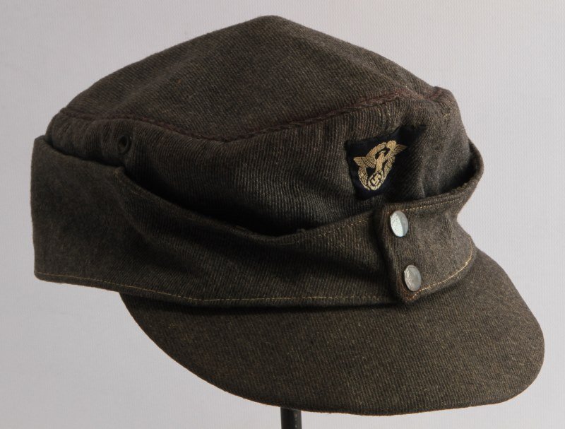 GERMAN WWII POLICE FIELD CAP THIRD REICH: German World War II Police M-43 field cap. The exterior is a grey cotton material with a machine embroidered BeVo police eagle sewn onto the front. It has a grey satin lining with two metal grommets. 
