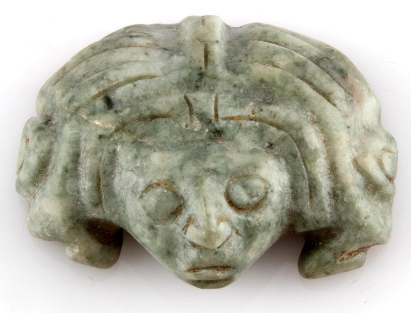 HUMAN HEAD EFFIGY JADE MAYA BELIZE PRE-COLUMBIAN: Pre-Columbian jadeite effigy depicting a human head with a headdress. Maya artifact. Measures 1.75 inches long by 2.5 inches wide. Acquired by a Louisiana Merchant Marine in 1950 or earlier. New river