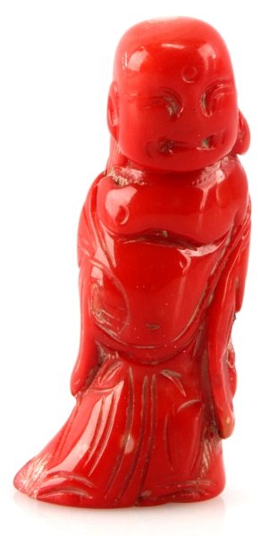 CHINESE RED CORAL FIGURE OF A BALD MAN IN ROBES: A red coral figure of a partially robed bald man. Stands just under 3 inches tall. In very good condition.