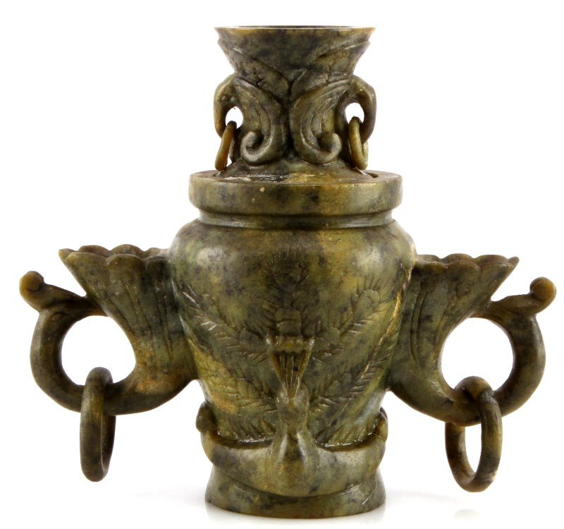 GREEN CARVED SOAPSTONE VASE WITH LID AND RINGS: Stands 6 inches tall by 6 inches wide. Has a peacock shaped handle and each side with a hanging ring. There is a larger peacock on both the front and the back. The lid is removable and has a peacock s