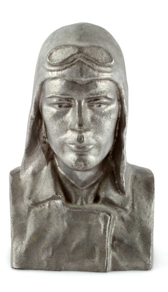 LINDY BANK CHARLES LINDBERG LUCKY LINDY BUST: Featuring a bust of the aviator wearing a flight helmet and goggles atop his head. The , white metal bank is 6.25" high. The back is marked "Lindy-Bank by G&T. 1928" and "N. Tregor," the sculptor's na