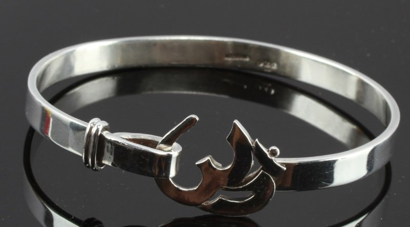 STERLING SILVER BUDDHIST OM BRACELET: A sterling silver bracelet with an Om clasp. Stamped "AJI STERLING 925" on interior of band. n very good condition. Fits wrists up to 7.5 inches in circumference. Weighs 24.8 grams.