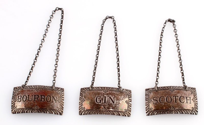 STERLING SILVER LIQUOR LABELS SCOTCH GIN BOURBON: Steiff sterling silver liquor labels for gin, scotch, and bourbon. The reverse are all hallmarked. Tarnished due to age but overall very good condition. They measure 2 inches wide.This lot has a reser