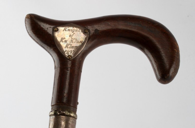 1897 KKK SILVER ADORNED SWORD STICK WALKING CANE: Pig sticker type blade, decorated silver wrap at sword scabbard, silver shield on handle reads "Knights of the Ku Klux Klan 1897", verso blood cross in silver shield. Measures 37 inches. Condition ver