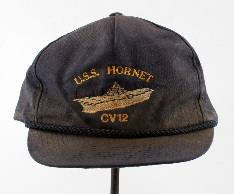 USS HORNET BASEBALL HAT SIGNED BY WWII VETERAN: Navy blue baseball cap with USS Hornet CV12 embroidery , signed by WWII fighter pilot John Latimer. The baseball cap is signed on the interior. Needs to be cleaned, but free from damage.