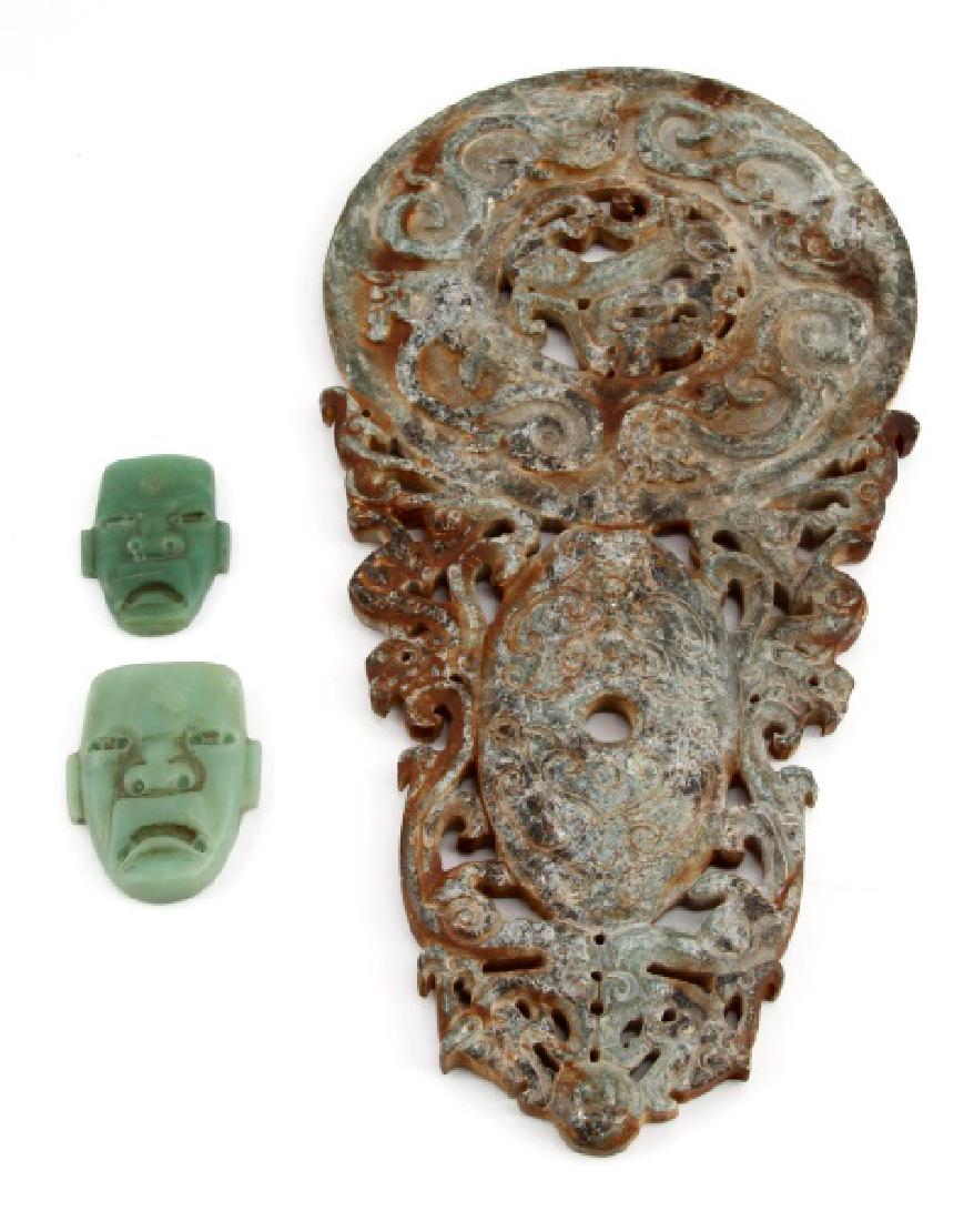 CENTRAL AMERICAN SOAPSTONE AND JADITE CARVINGS: A high relief carved soapstone platter or large pendant and two smaller jadeite mask pendants. The soapstone piece measures 12-3/4 inches (32.5 cm) long by 6-1/2 inches (16.5 cm) at the widest. The so