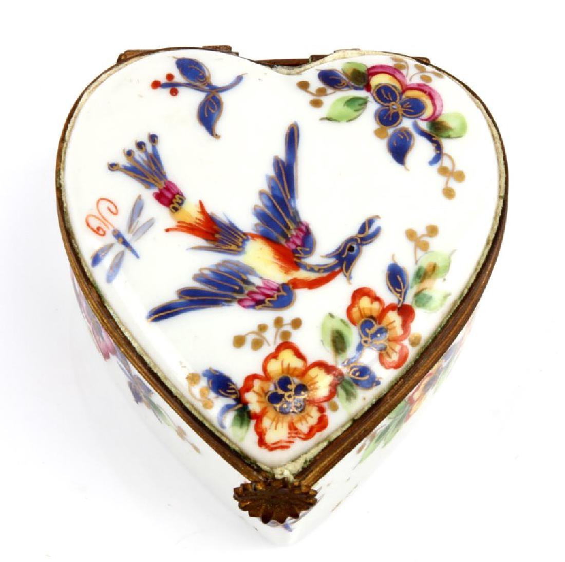 LE TALLEC PORCELAIN BOX FROM LYNDHURST PLANTATION: Hand-painted, heart-shaped, porcelain with brass jewelry or trinket box with floral designs, dragonflies, and a Bird of Paradise in flight on the lid. The bottom of the piece bear the hand-drawn inscr