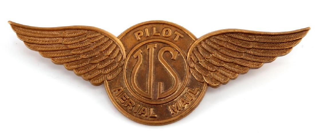 1920S US AERIAL MAIL PILOT WING BADGE: A 1920s United States Aerial Mail Pilot Wing badge measuring 3-1/2 inches wide by 1-1/4 inches tall. The reverse of the brass badge has a thin, horizontal, 180-degree lie pin back. The bade is in good