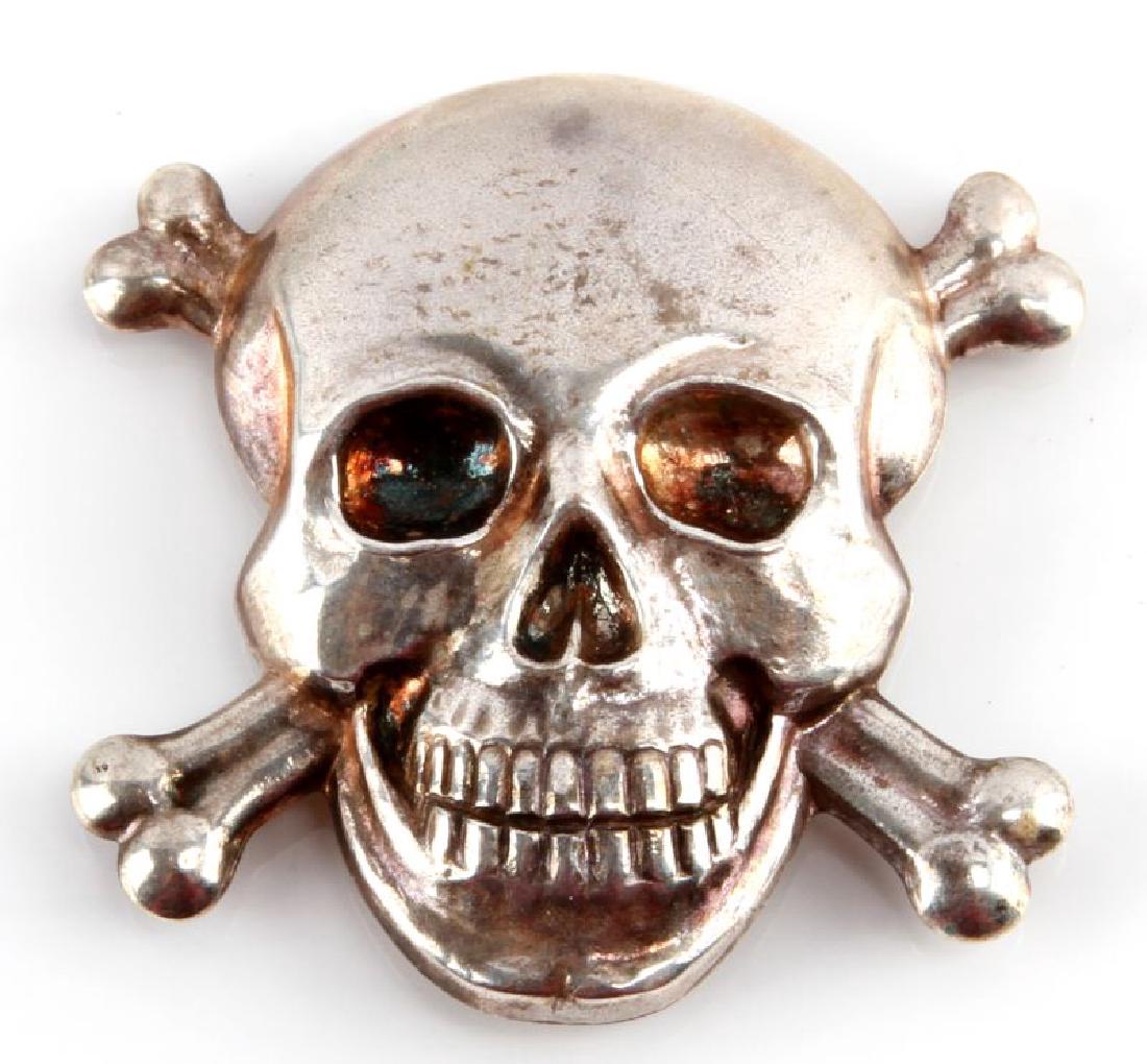 WWII ITALIAN FASCIST SKULL & CROSS BONES CAP BADGE: A WWII Italian Fascist Skull and Crossed Bones Visor Cap Badge measuring 1-15/16 inches tall by 1-15/16 inches wide. The reverse of the silver plated nickel badge has 4 round, thin mounting prongs. Un