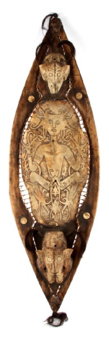ANTIQUE DAYAK FRESHWATER TURTLE SHELL WAR SHIELD: A war shield from the Dayak tribes of Sarawak (Borneo) measuring 40 inches long by 12 inches wide at the center. The design incorporates a carved hardwood frame, the bottom shell of a Borneo freshwate