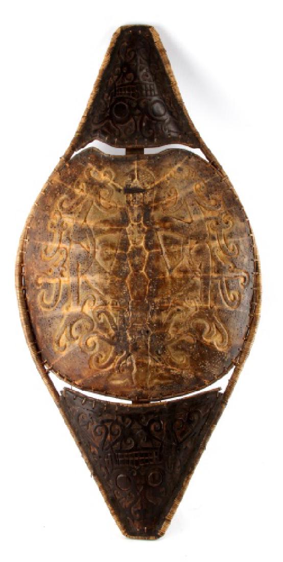 BORNEO DYAK FRESH WATER TURTLE SHELL WAR SHIELD: A war shield from the Dayak tribes of Sarawak (Borneo) measuring 36 inches long by 17 inches wide at the center. The design incorporates 5 pieces: a cord-wrapped, bent-wood frame, the top shell of a B