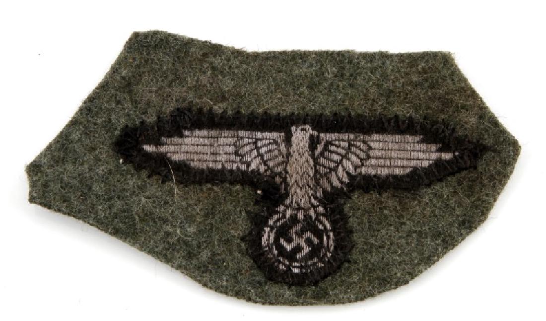 GERMAN WAFFEN SS EM CAP EAGLE CUT FROM AN M-43 CAP: German WWII Waffen SS EM Cap Eagle Cut from an M-43 Cap. Measures 3 5/8" wide by 2" tall. Machine sewn zig zag stitched on an OD green wool backing. Unauthenticated, sold as is.