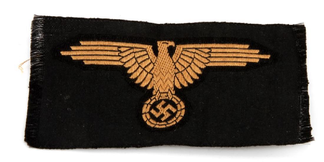 GERMAN WWII WAFFEN SS TROPICAL EM ARM EAGLE: German WWII Waffen SS Tropical EM arm eagle. Measures 4" wide by 1 7/8" tall. Bevo embroidered on a black rayon backing. Uncut from a roll. For an enlisted man. Unauthenticated, sold as is.