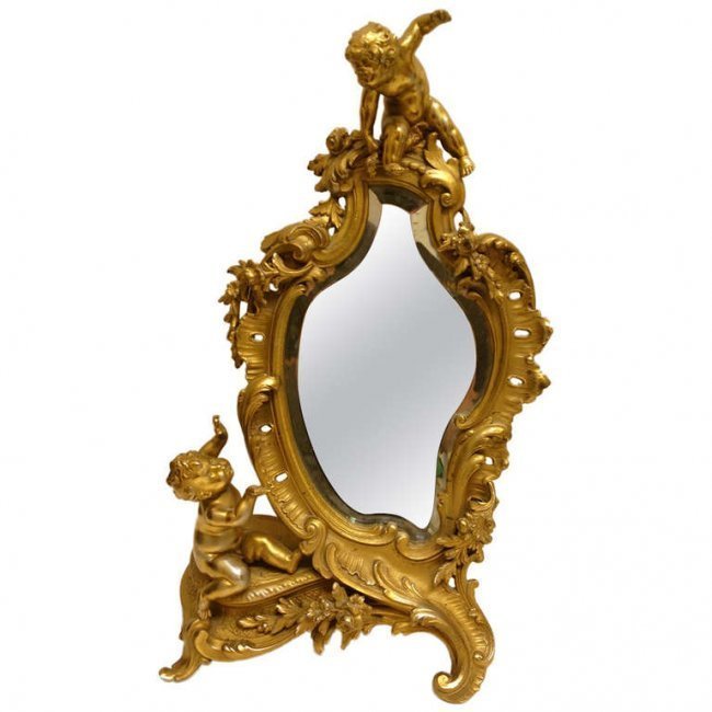 Jewelers or Dressing Table Mirror Putti France c1940: The subject matter of Putti assisting to direct the looker is undeniably charming On this dressing mirror, finely cast with its original beveled mirror. With slight rubbing to the gold from handling.1