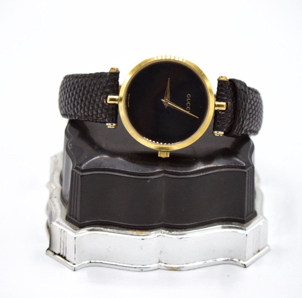 Gucci swiss made gold laminated ladies' wristwatch: Gucci Swiss made gold laminated ladies' wristwatch, c. 1980. Face and casing back are in onyx, The watch bezel is 30 mm in diameter and 7mm deep. The leather band is a replacement and is 8 mm wide and