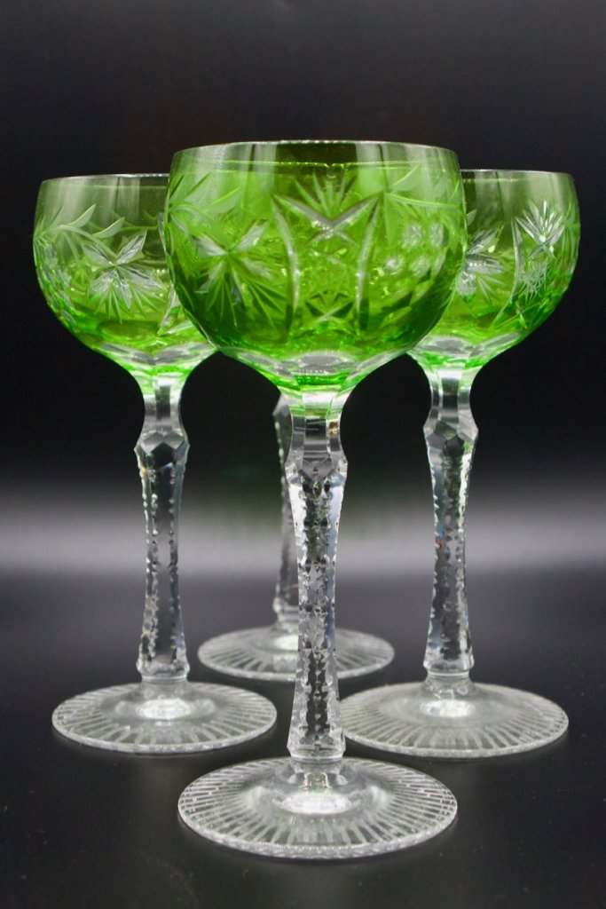 Four count Bohemian green cut to clear wine glasses: Four count Bohemian green cut to clear hock wine glasses, circa 1925. Glassware has a meandering grape vine cut glass pattern on bowl and six-sided clear stems with notch cut edges. Glasses terminate 