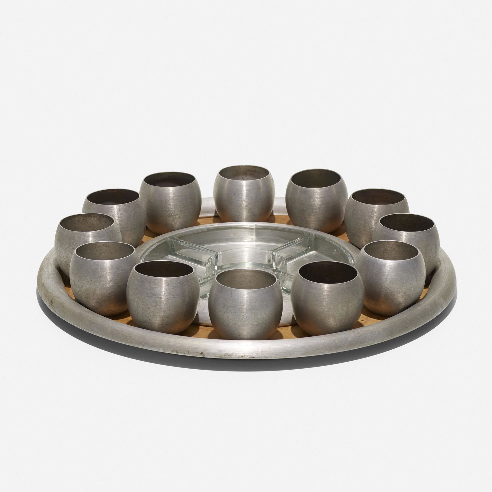 Russel Wright, serving set: Russel Wright serving set USA, c. 1945spun aluminum, glass, birch3.5 h × 21 dia in (9 × 53 cm) Set includes one tray, four glass inserts and twelve cups measuring: 3 h x 3.5 dia inche