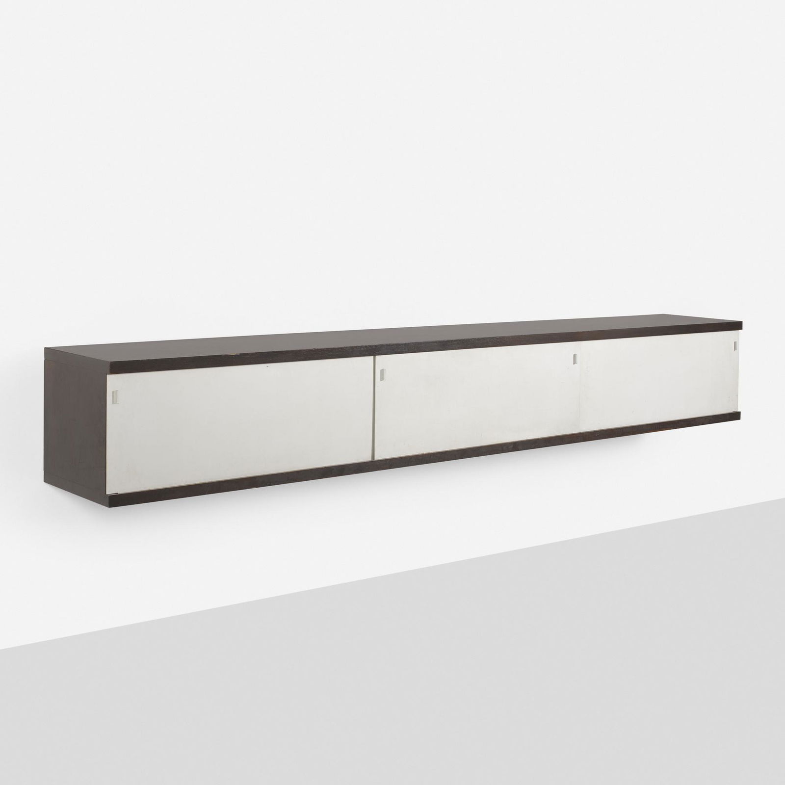 Horst Bruning, Wall-mounted cabinet: Horst Bruning Wall-mounted cabinet BehrGermany, c. 1965cocobolo veneer, aluminum126.25 w × 18 d × 17.75 h in (321 × 46 × 45 cm) Cabinet features three sliding doors