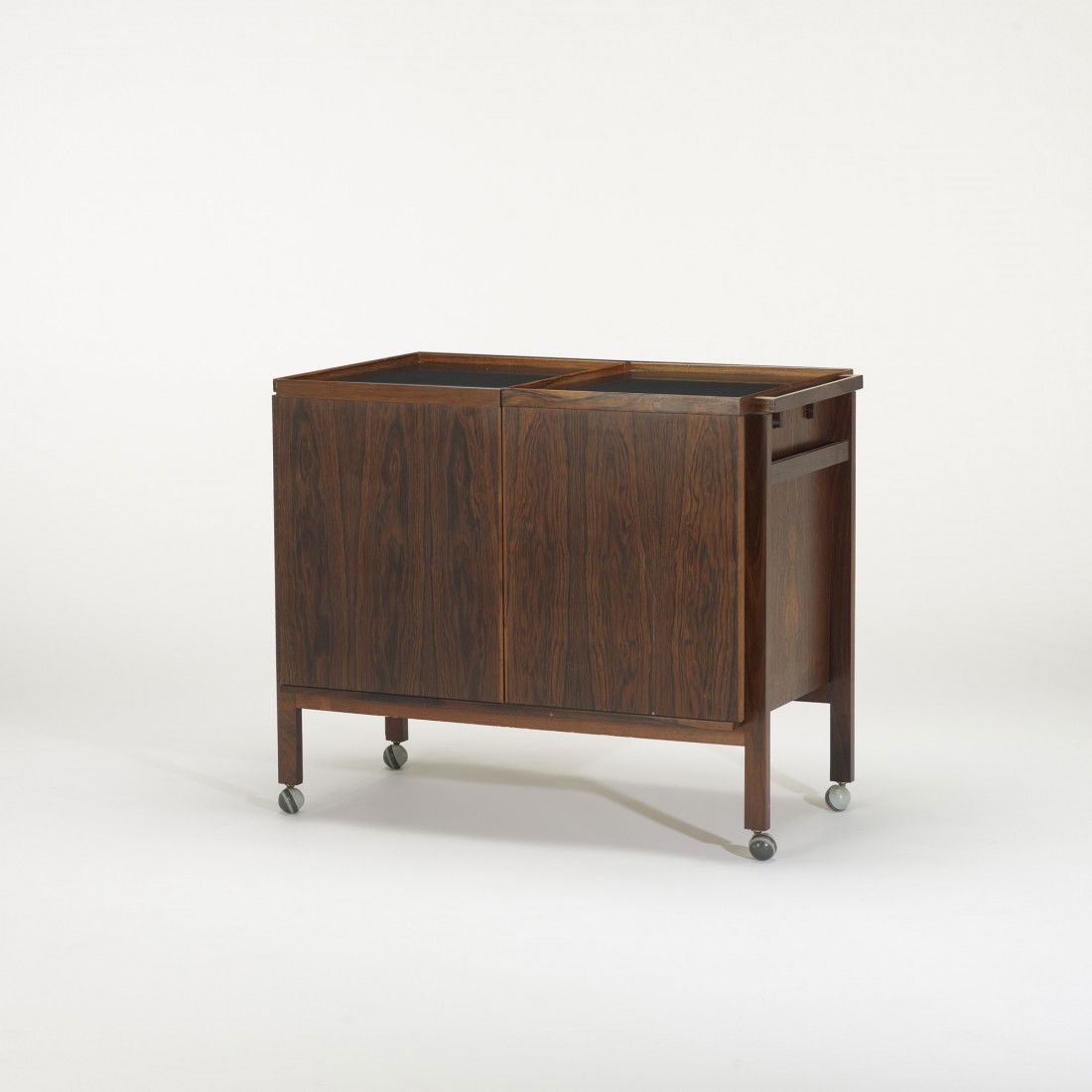 Modern bar cart: Modern bar cart USA, c. 1970 rosewood, laminate, plastic 34.5 w x 20 d x 28.5 h inches Bar cart features two sliding doors concealing storage.