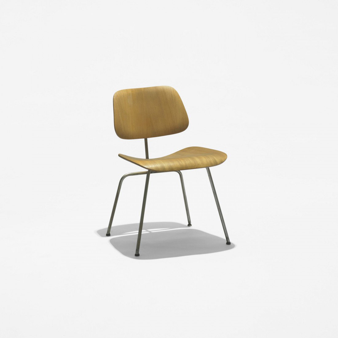 Charles and Ray Eames DCM: Charles and Ray Eames DCM Evans Products USA, 1946 Calico ash plywood, chrome-plated steel, rubber 19.5 w x 21 d x 29.5 h inches This early example features a lap-jointed frame with large circular met