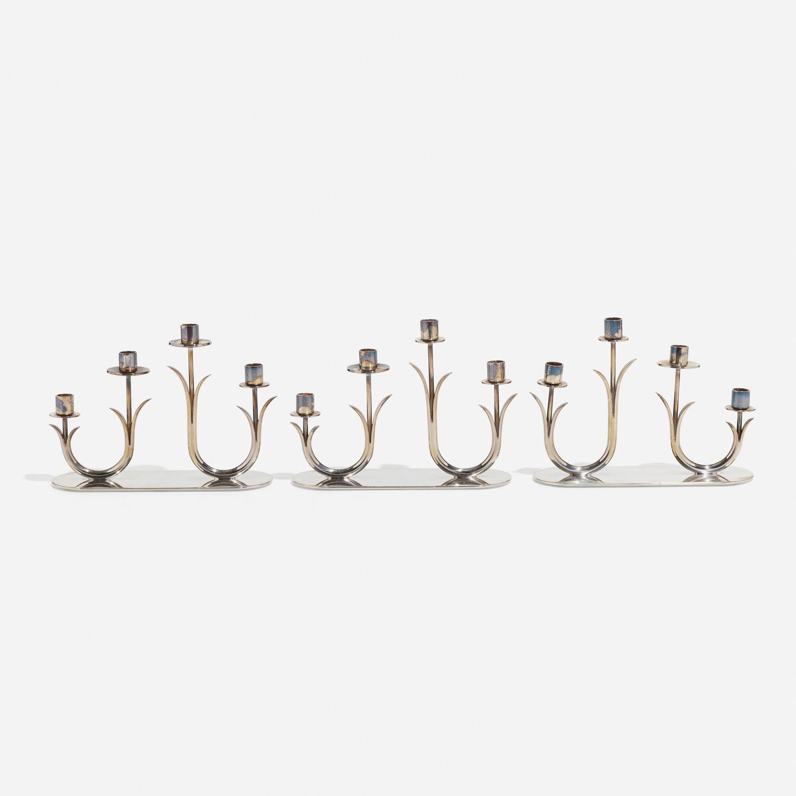 Gunnar Ander, Candelabra, set of three: Gunnar Ander Candelabra, set of three Ystad-MetallSweden, c. 1960silver plated brass 5.25 h x 7 w x 2.5 d in (13 x 18 x 6 cm) Impressed manufacturer's mark to underside of each example '