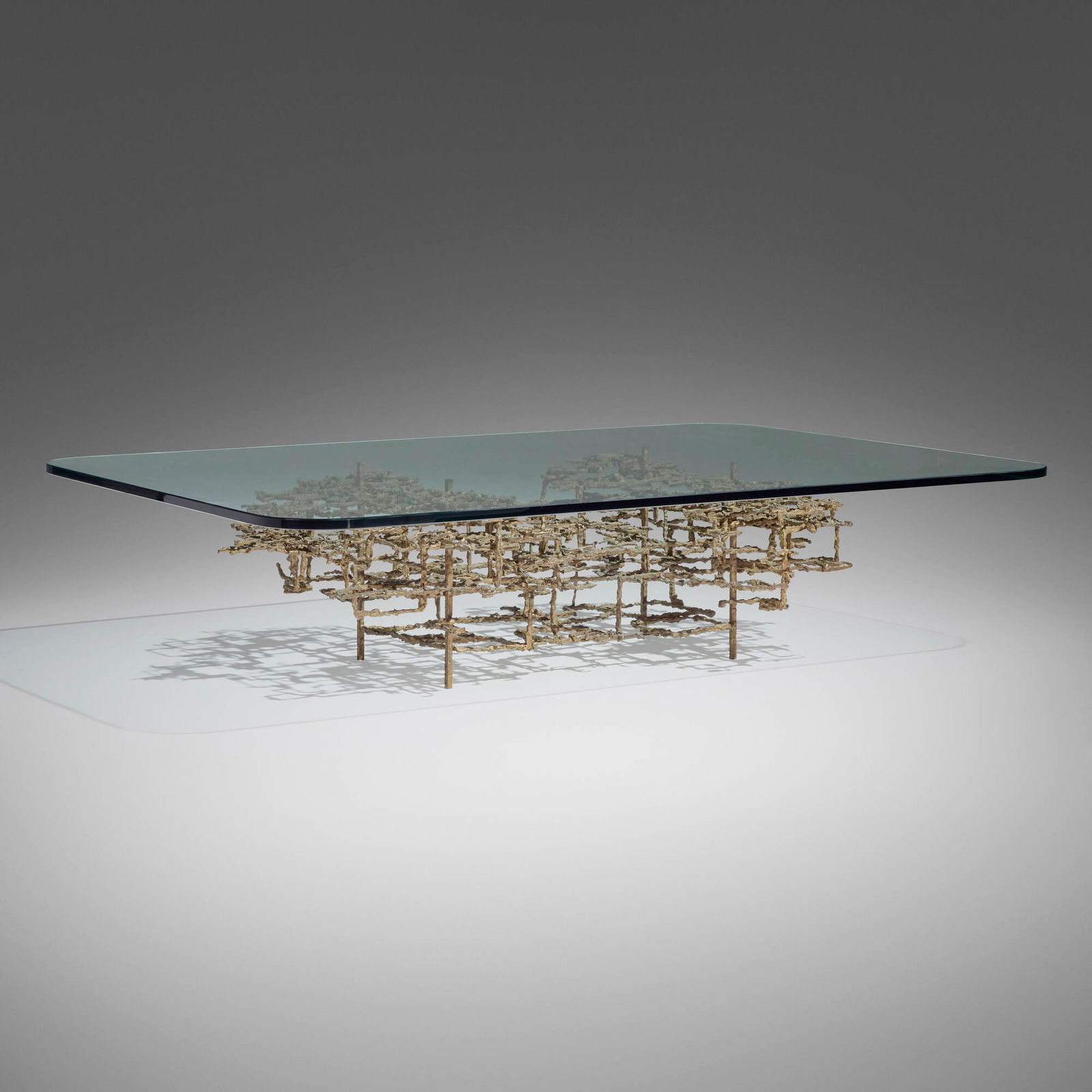 Daniel Gluck, Sculptural coffee table: Daniel Gluck Sculptural coffee table USA, c. 1970sculpted bronze, glass 15.5 h x 66 w x 45 d in (39 x 168 x 114 cm) Impressed signature to top of base 'Gluck'. Provenance: