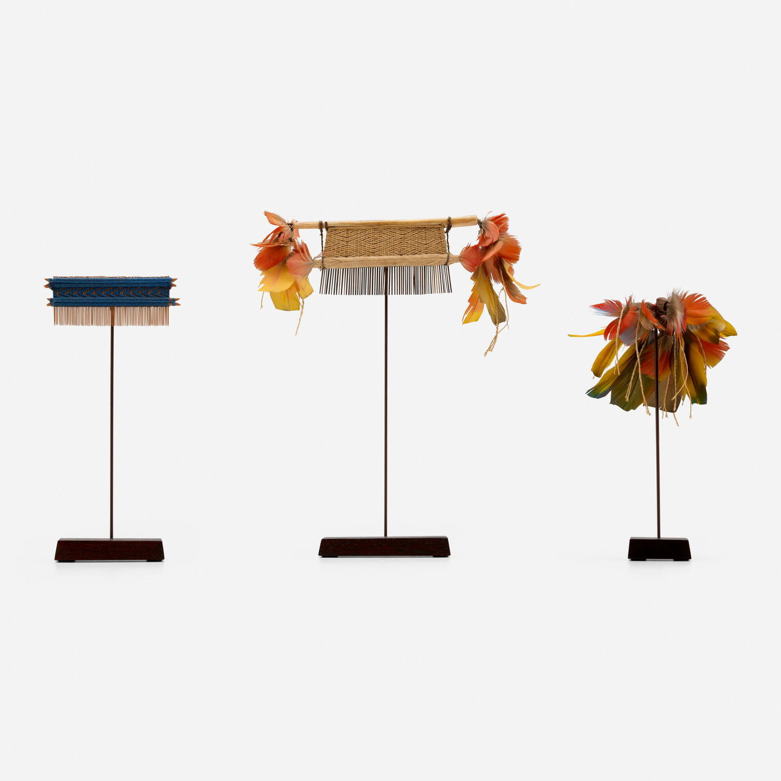 Brazilian, Collection of two Hixkaryana combs and one ear ornament: Brazilian Collection of two Hixkaryana combs and one ear ornament 20th centuryfeathers, woven fiber, bone, beads, seed pods 10.5 h x 9 w x 1.75 d in (27 x 23 x 4 cm) 7.75 h x 3.75 w x 1.5 d in (20