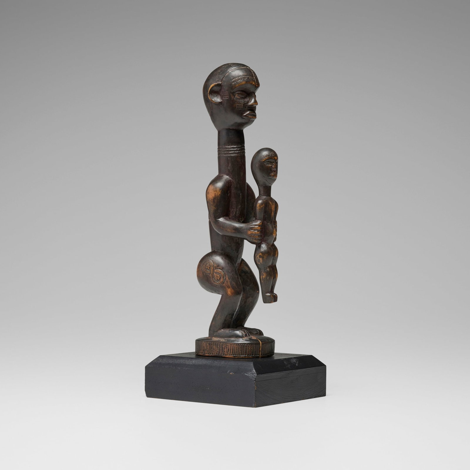 Bena Lulua, Figure with child: Bena Lulua Figure with child Democratic Republic of the Congo, 20th century carved wood 12.5 h x 2.75 w x 3.5 d in (32 x 7 x 9 cm) Sold with base. Provenance: Collection