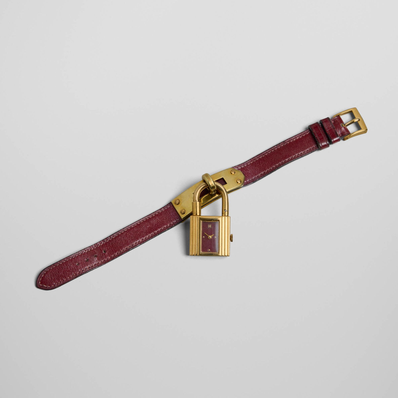 Hermes, Kelly padlock wristwatch: Hermes Kelly padlock wristwatch France / Switzerland, c. 1980gold-plated steel, leather case: 1.5 h x 1 w in (4 x 3 cm) strap: 6.875 l in (17 cm) Painted manufacturer's mark to dial 'H Swis