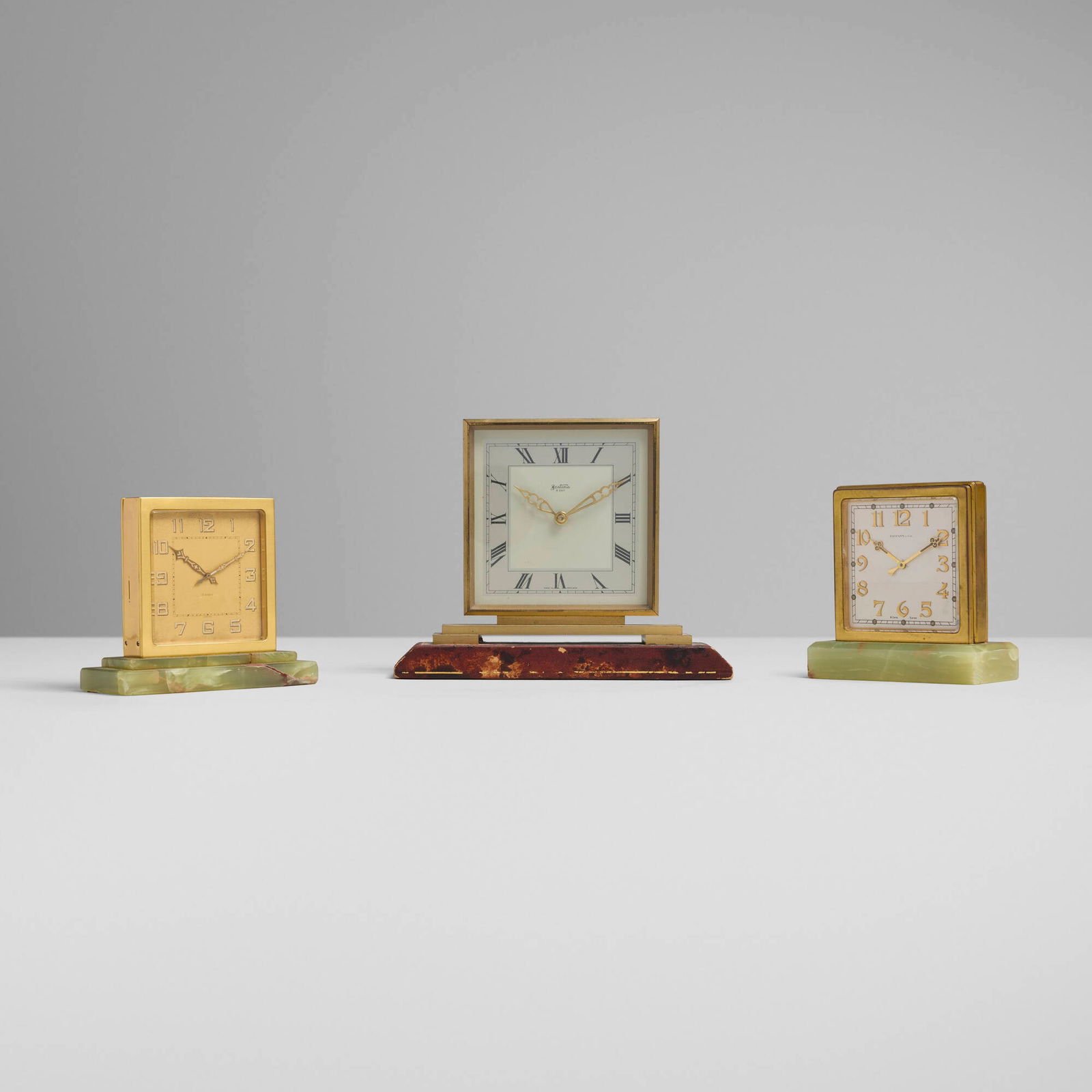 Art Deco, Collection of three table clocks: Art Deco Collection of three table clocks c. 1935gilt brass, onyx, stone, leather 7 h x 9 w x 2.75 d in (18 x 23 x 7 cm) 5.25 h x 5 w x 2.25 d in (13 x 13 x 6 cm) 5 h x 5.5 w x 2.5 d in (13 x 1