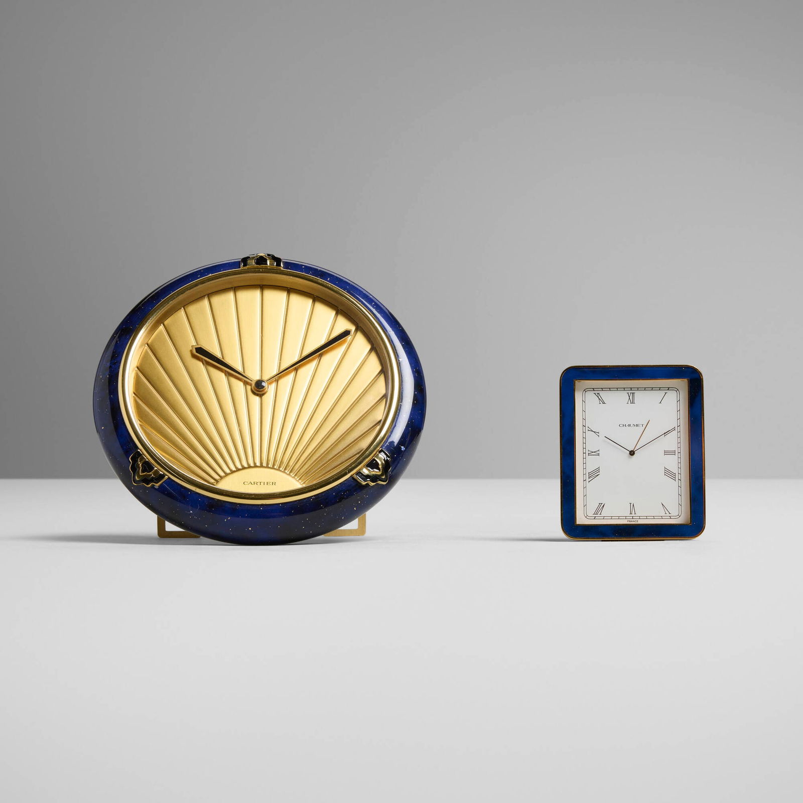 Cartier and Chaumet, Desk clocks, set of two: Cartier and Chaumet Desk clocks, set of two France, c. 1989-2000 gilt brass, enamel, acrylic, lacquer 5 h x 5 w x 3 d in (13 x 13 x 8 cm) 2.75 h x 2 w x 0.75 d in (7 x 5 x 2 cm) Set is comprised