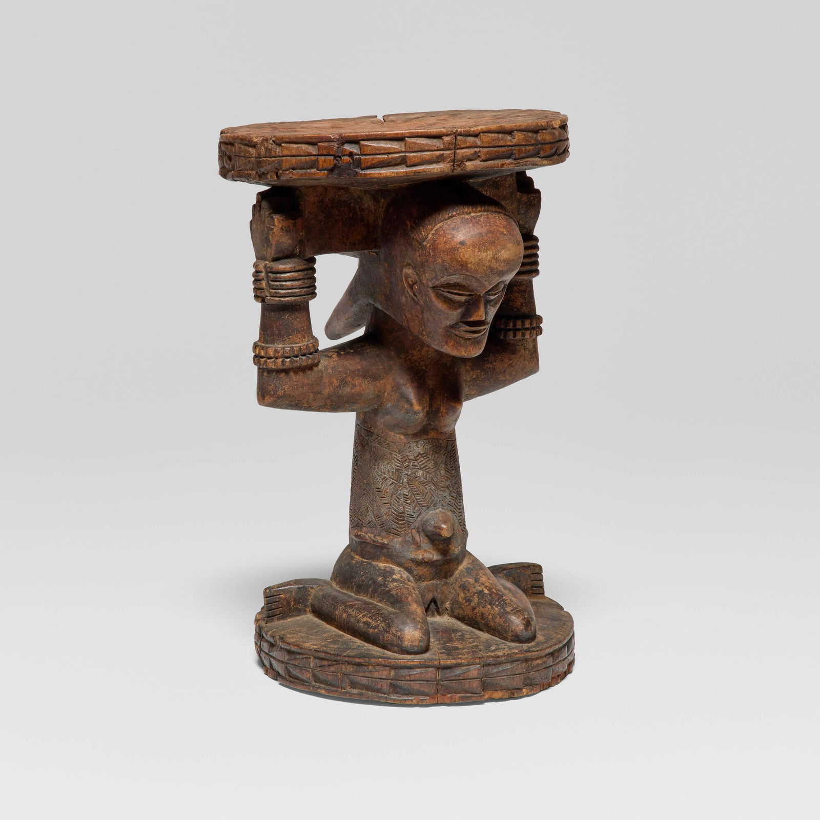 Luba, Caryatid stool: Luba Caryatid stool Democratic Republic of Congo, 20th century carved wood 16.5 h x 10.25 dia in (42 x 26 cm) Carved as a kneeling female caryatid raising both arms to support the circular seat,
