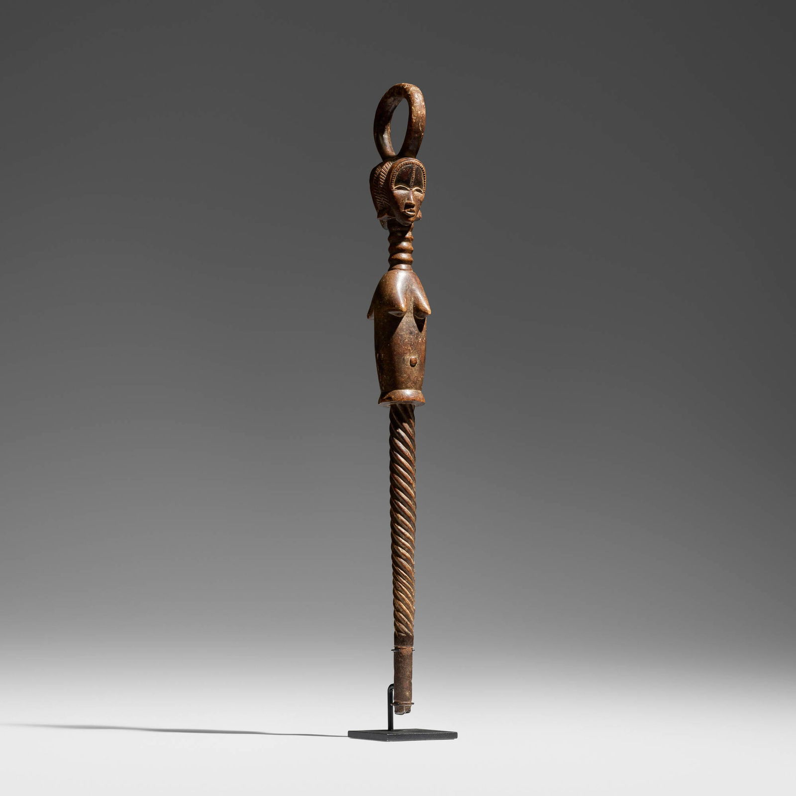 Baule, Janus staff: Baule Janus staff Cote d'Ivoire, early 20th century carved wood, kaolin, pewter 36 h x 3 w x 4.5 d in (91 x 8 x 11 cm) This finely carved staff retains its original metal tip. Provenance: