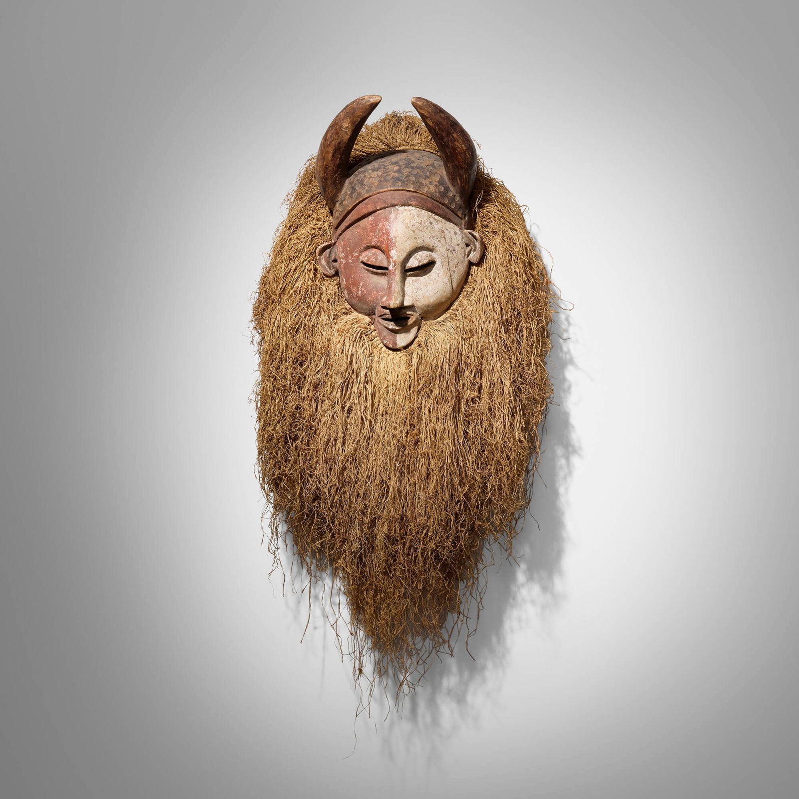 Holo, Circumcision mask: Holo Circumcision mask Democratic Republic of Congo, 20th centurycarved wood, pigment, raffia 46 h x 24 w x 11.5 d in (117 x 61 x 29 cm) Provenance: Collection of Dr. Robert a
