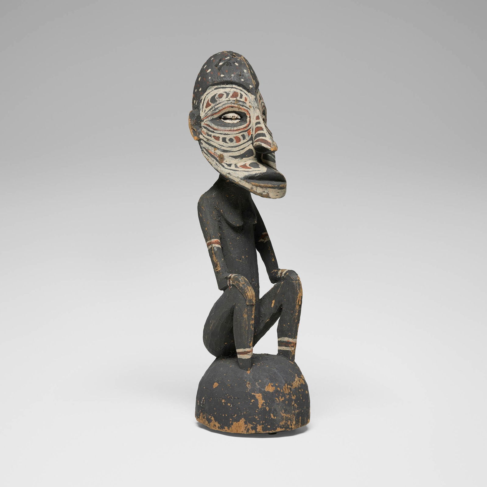 East Sepik, Seated Figure: East Sepik Seated Figure New Guinea carved and painted wood, cowrie shells 15 h x 4 w x 4.5 d in (38 x 10 x 11 cm) Provenance: P.N.G. Art, Papua New Guinea | Acquired from the previous in 1992,