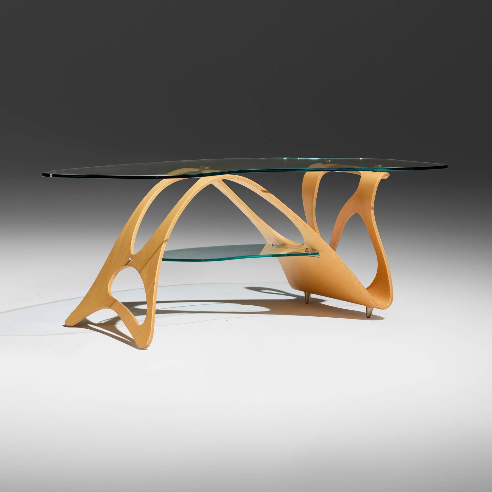 Carlo Mollino, Arabesco coffee table: Carlo Mollino Arabesco coffee table Zanotta Italy, 1949 / after 1990 oak plywood, glass, stainless steel 17.5 h x 50.5 w x 20 d in (44 x 128 x 51 cm) Provenance: Collectio