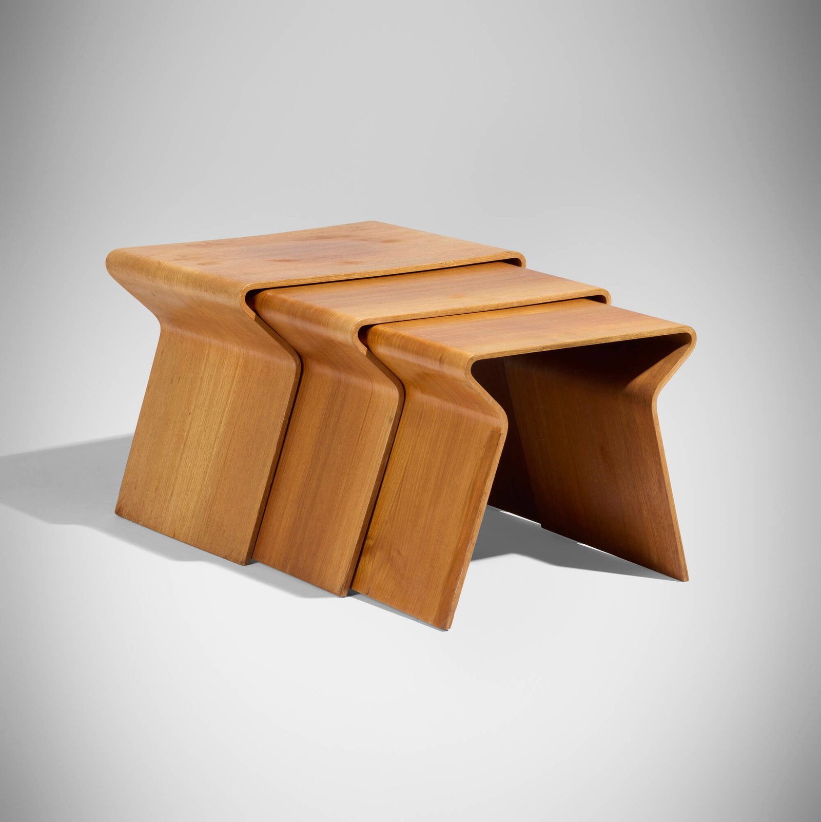 Grete Jalk, Rare nesting tables, set of three: Grete Jalk Rare nesting tables, set of three Poul Jeppesen Denmark, 1962 bent plywood with teak veneer 16.375 h x 30.75 w x 14.5 d in (42 x 78 x 37 cm) Branded manufacturer's marks to