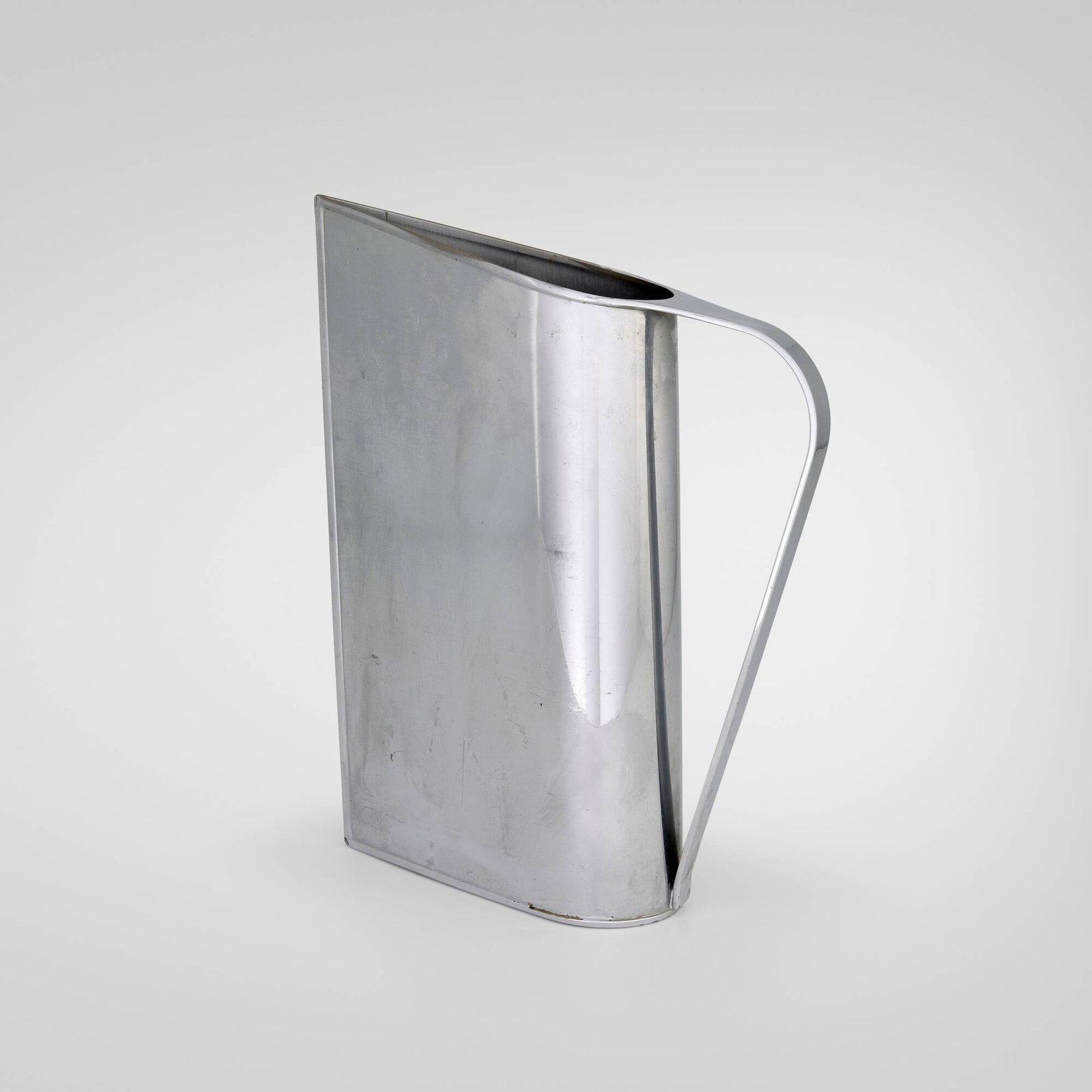 Peter Muller-Munk, Normandie pitcher: Peter Muller-Munk Normandie pitcher Revere Copper and Brass, Inc. USA, 1935 chrome-plated brass 12 h x 3 w x 10 d in (30 x 8 x 25 cm) Impressed manufacturer's mark to underside 'Revere Rome