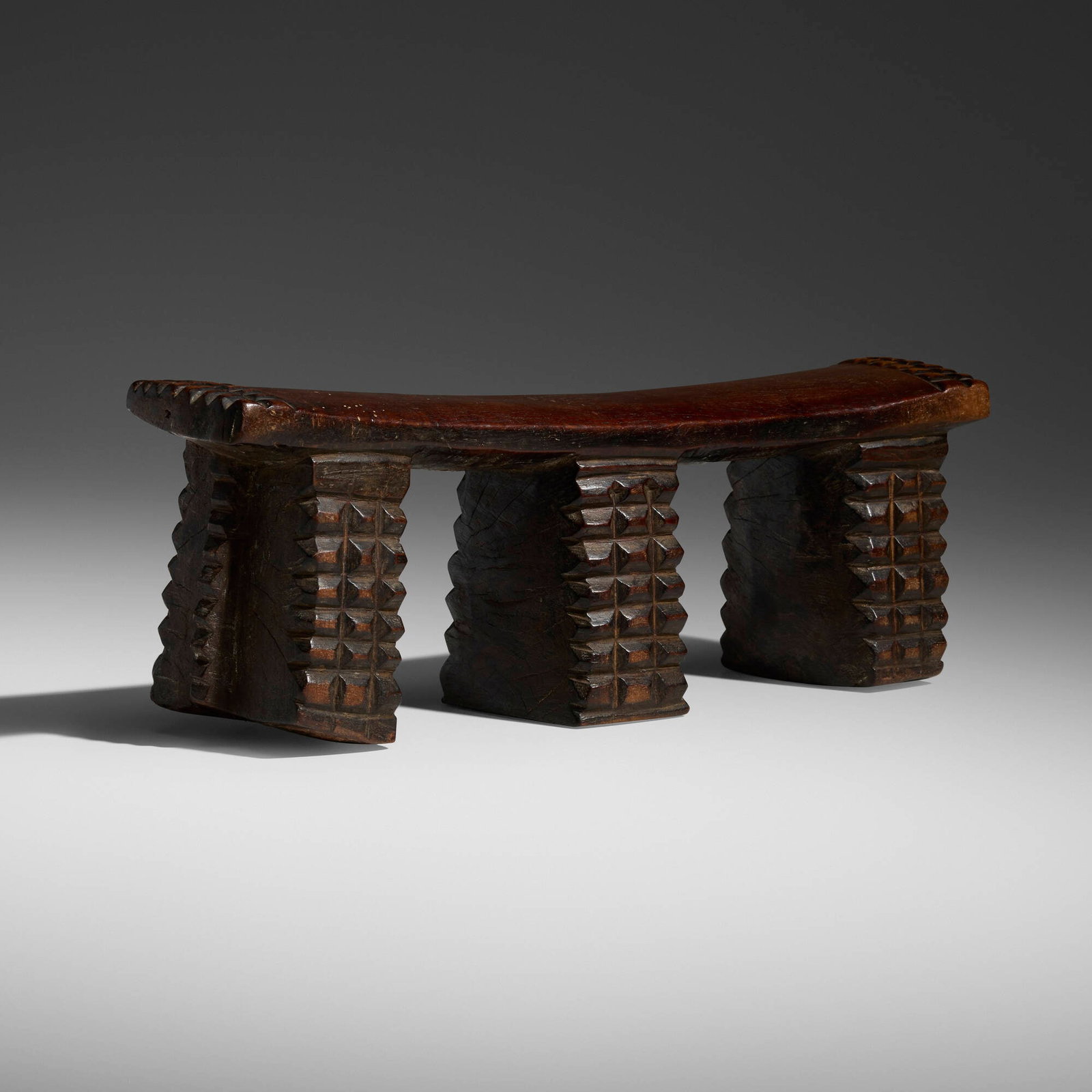 Zulu, Headrest: Zulu Headrest South Africa, 20th century carved wood 5 h x 14 w x 3.5 d in (13 x 36 x 9 cm) This three-legged Zulu headrest has a rich patina and is carved with diamond-shaped amasumpa