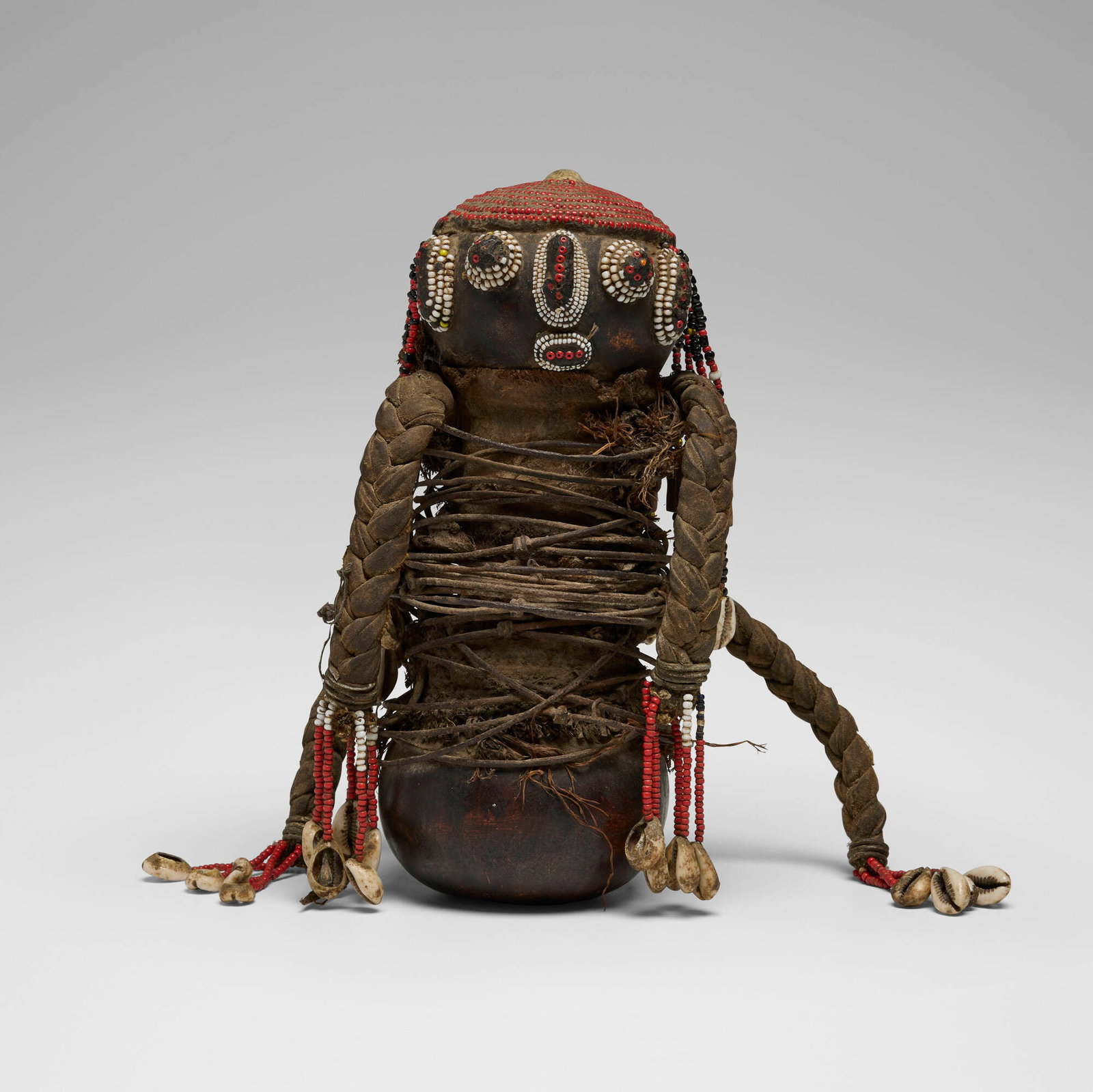 Nyaturu, Gourd figure: Nyaturu Gourd figure Tanzania, 20th century gourd, cowry shell, beads, raffia, metal 10 h x 6 w x 5 d in (25 x 15 x 13 cm) These gourd figures were traditionally hung in the rafters of a home to