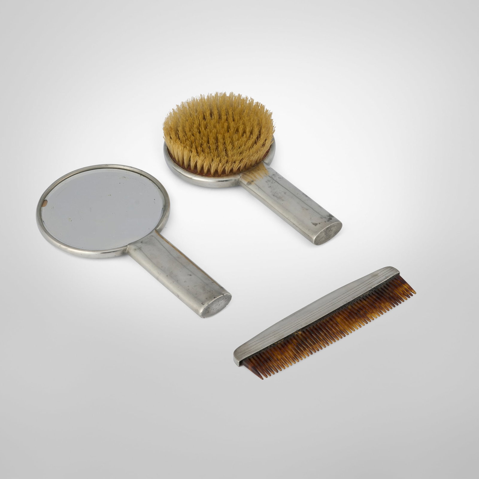 Queens Art Pewter, Vanity set: Queens Art Pewter Vanity set USA, c. 1935 pewter, mirrored glass, celluloid 9.25 h x 5 w x 0.75 d in (23 x 13 x 2 cm) 8.75 h x 4.375 w x 1.5 d in (22 x 11 x 4 cm) 7.25 h x 2 w x 0.25 d in (18 x 5 x 1