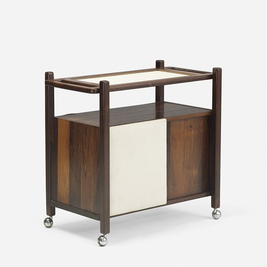 Sergio Rodrigues bar cart: Sergio Rodrigues bar cart Brazil, c. 1960 rosewood, laminate, upholstery, chrome-plated steel 29.5 w x 16.5 d x 27.75 h inches Bar features two upholstered sliding doors, one concealing a single shelf