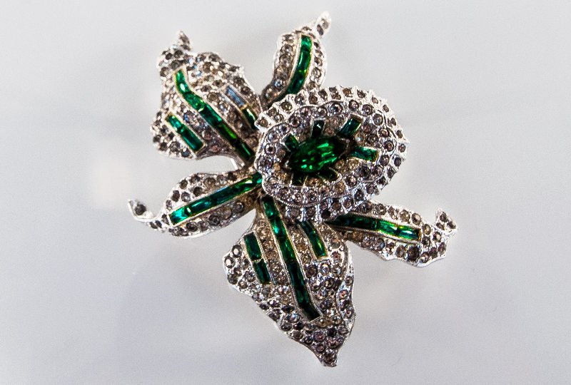 rare Art Deco Costume Tremblanc brooch by TKF.: This is a rare Art Deco Costume Tremblanc brooch by TKF. (Trifari, Krussman & Fishel). The brooch features a large orchid design accented with inlaid green rhinestones. It is framed with pave set roun