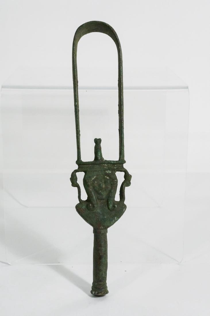 ANCIENT EGYPTIAN BRONZE SISTRUM: Probably 600-400 B.C The hoop-shaped form with a cat at the base, the cylindrical handle surmounted by a two-faced Hathor head above an aegis flanked by two upreared cobras wearing the Double Crown, E