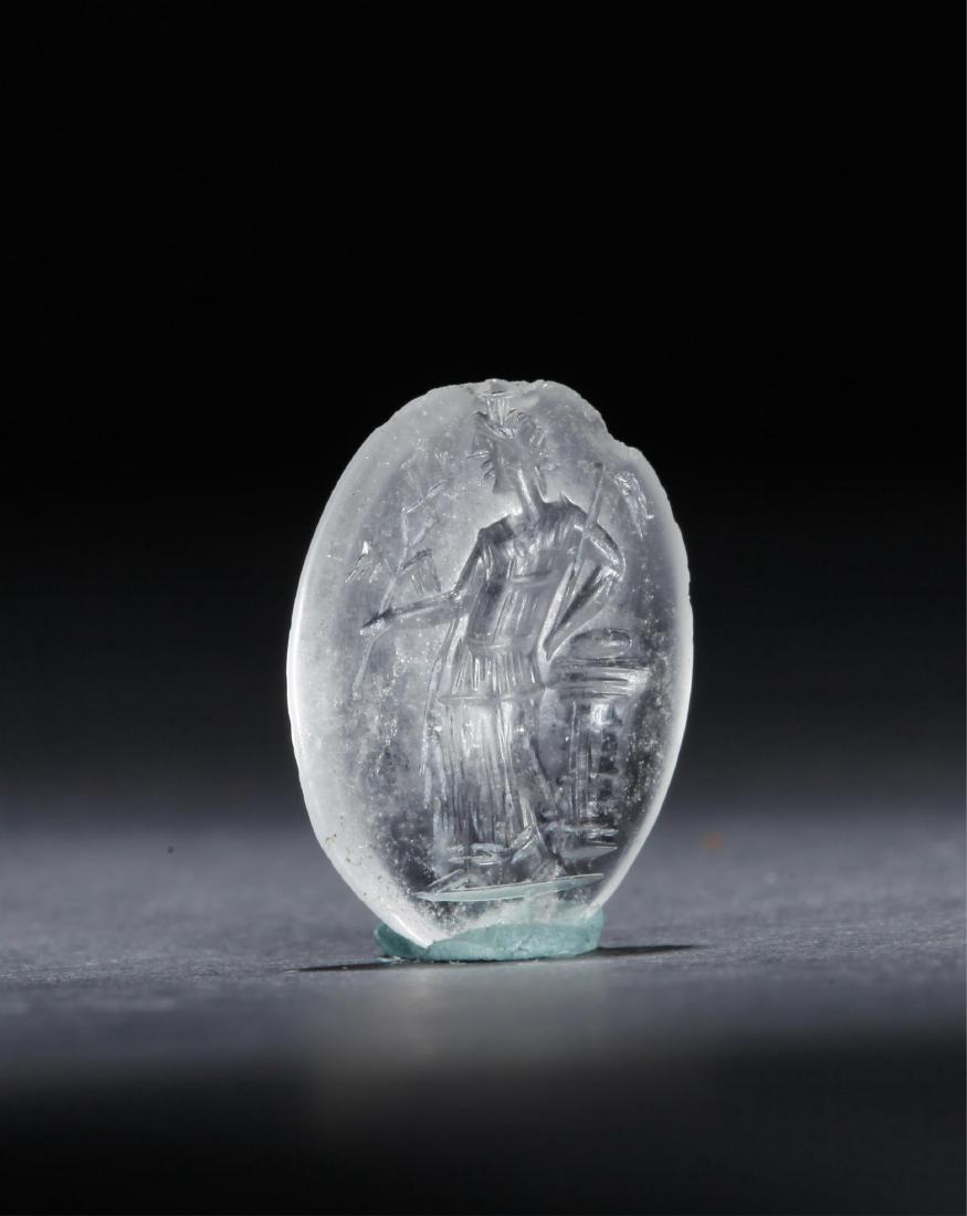 CRYSTAL INTAGLIO WITH PANTHEISTIC GODDESS: Roman Empire (1st - 3rd Century AD) Material: Crystal. 1.9cmx1.4cm The goddess is wearing a kiton and a high crown similar to that of the Serapis. She is reclining to a pillar, with a snake staff in o