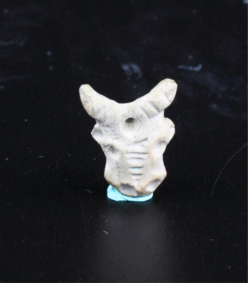 WHITE STONE AMULET OF A BULL CRANIUM: Late Period (7th - 4th Century BC) Material: White stone. 1.7cmx1.4cmx0.7cm . Condition: Intact.