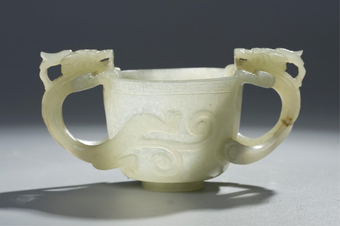 A CELADON TWIN DRAGON JADE CUP, MING DYNASTY: ming dynasty, with one natural hairline on dragon's tail. Height: 6cm, length: 11cm, mouth diameter: 6cm, bottom diameter: 2cm Provenance: Long Island Estate
