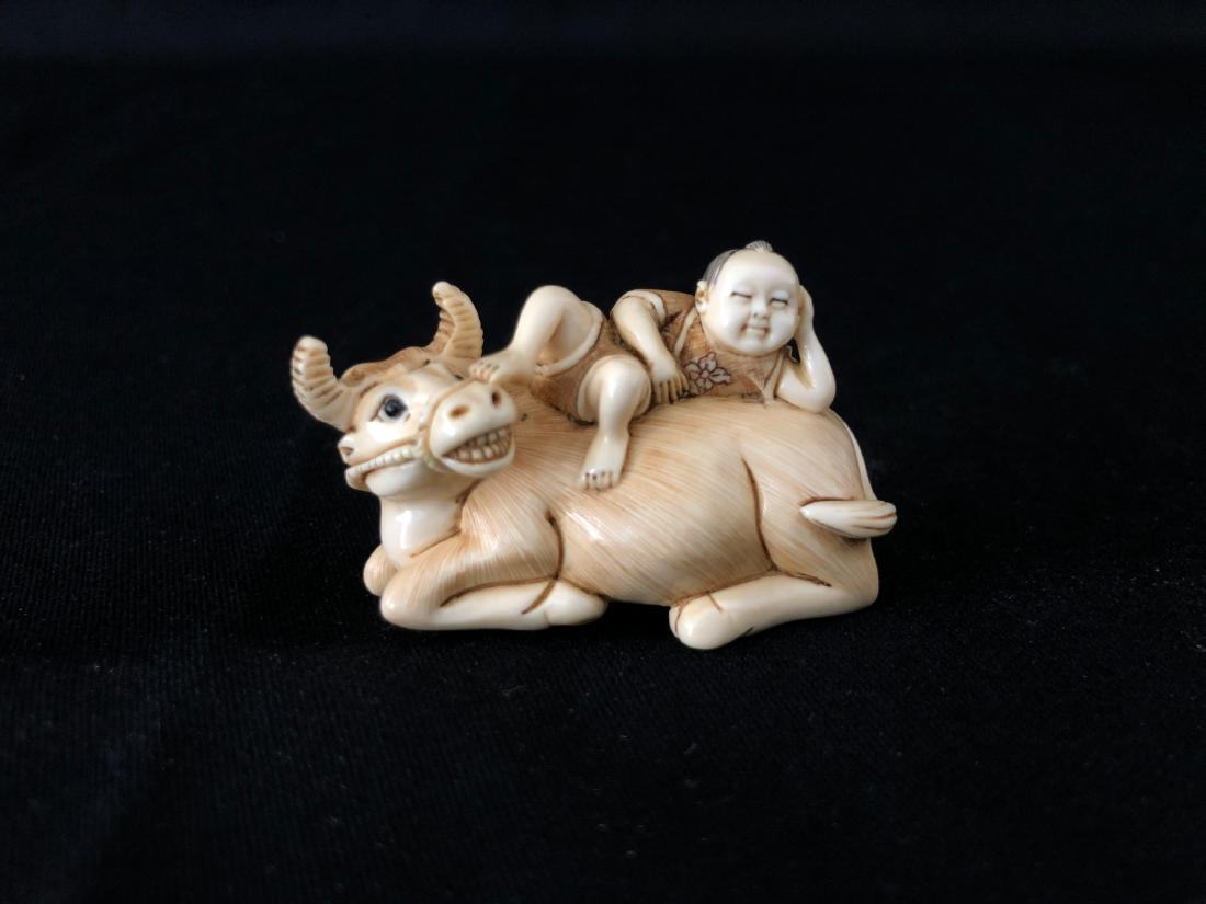 A Cattle Bone Carved Netsuke of Ox and Boy: A Cattle Bone Carved Netsuke of Ox and Boy. H: 1.15 in. (2.8 cm.) W: 1.75 in. (4.4 cm.) D: 1 in. (2.5 cm.)