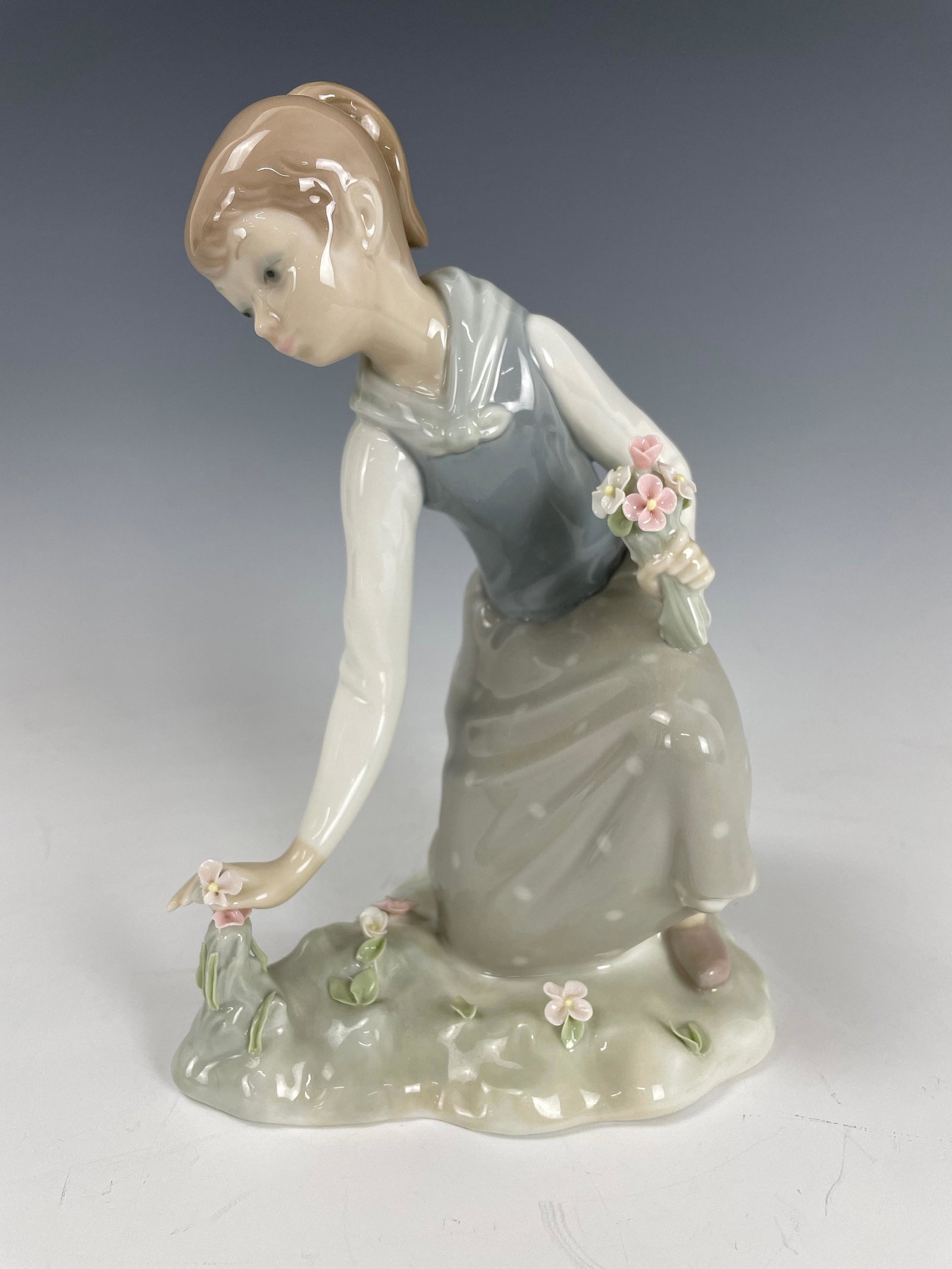 Lladro Figurine of A Girl Picking Flowers: Lladro Figurine of A Girl Picking Flowers,H 19 cm. (7.8 in.), preview from Jun 6th to 10th from 2:00 PM TO 6:00 PM Eastern Time, Location: 15229 Display Court Rockville MD 20850.