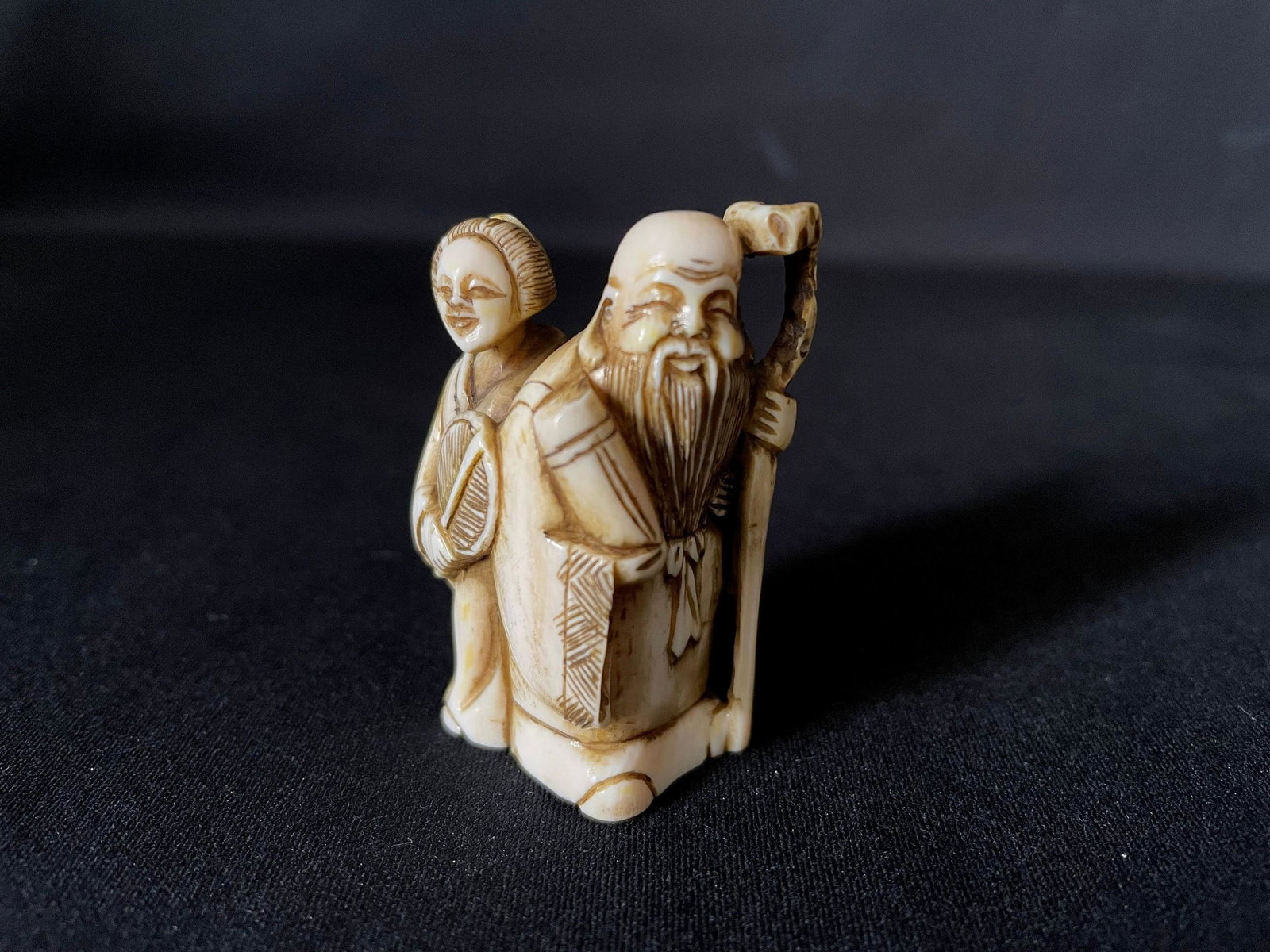 A Carved Cattle Bone Netsuke of Elder Couples: A Carved Cattle Bone Netsuke of Elder Couples. H: 2 in. W: 1.5 in. D: 0.75 in